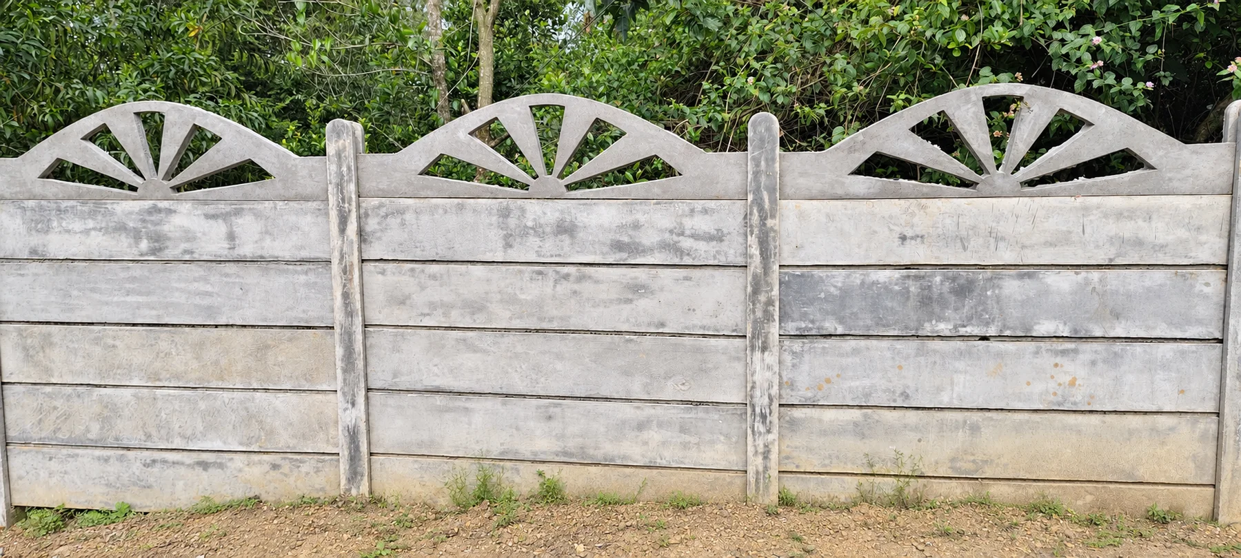 Installed precast concrete compound wall with horizontal panels, posts and decorative fan-shaped tops